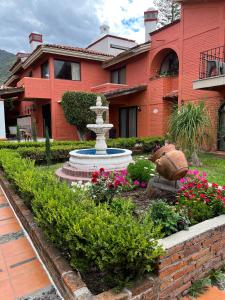 阿吉吉克Hotel Villas Ajijic, Ajijic Chapala Jalisco的一座花园,位于一座带喷泉的房屋前