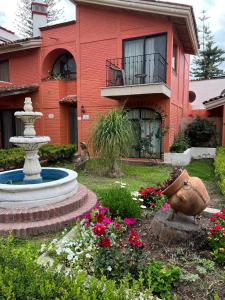 阿吉吉克Hotel Villas Ajijic, Ajijic Chapala Jalisco的一座带喷泉和鲜花的花园的房子