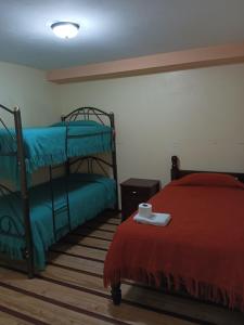 里奥班巴Hostal Puertas Del Sol的一间卧室设有两张双层床和红色毯子