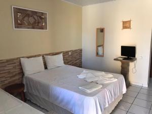 普拉亚弗朗西丝Torre do Sol的一间卧室配有一张带白色床单的床和电视。