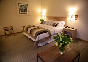 塔尔卡卡斯罗塔尔卡酒店的一间卧室配有一张大床,桌子上放着花瓶