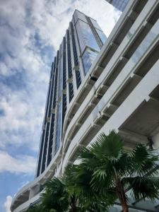 巴淡岛中心Alexa Meisterstadt pollux habibie的一座高大的建筑,前面有一棵棕榈树