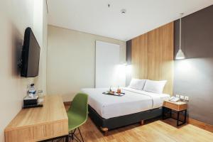 三宝垄三宝垄奇特拉瑞姆酒店的一间卧室配有一张床、一张书桌和一台电视
