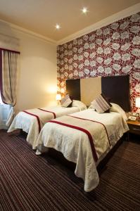 特伦南海滩酒店的两张位于酒店客房的床,配有红色和白色的壁纸