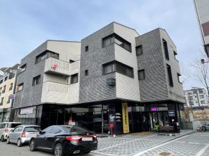 仁川市Koin Guesthouse Incheon airport的前面有汽车停放的建筑