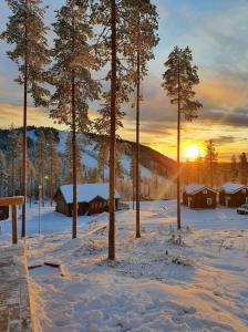 哈拉斯Stuga i Storklinten的一片雪地,满是房屋和树木,享有日落美景