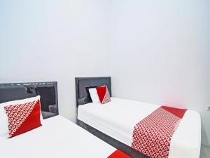 美娜多SPOT ON 91995 Cvictory Inn的两张带红色和白色枕头的床