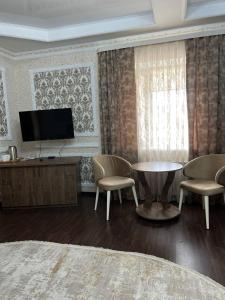 库斯塔奈Grand SPA Hotel的客厅配有电视和桌椅