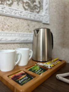 库斯塔奈Grand SPA Hotel的茶壶和木切板上的两杯