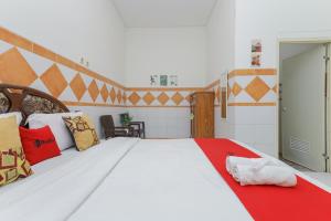 MojokertoRedDoorz Syariah at Mojosari的卧室配有一张带彩色枕头的大型白色床。