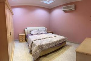 哈伊勒شالهيات ريست 2的卧室配有一张床铺,位于一间粉红色墙壁的房间