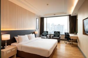 曼谷曼谷茉莉花度假酒店的酒店客房,配有一张床、一张桌子和椅子