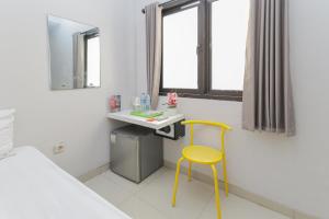 泗水RedDoorz Plus At K23 Rungkut Madya的一间设有黄色椅子和一张书桌的房间