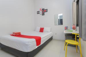 泗水RedDoorz Plus At K23 Rungkut Madya的一间卧室配有一张床和一张黄色椅子