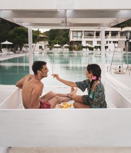 孔图尔西泰尔梅罗莎佩佩酒店的坐在游泳池旁的船上的男人和女人
