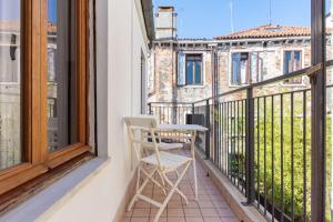 威尼斯San Marco Bell Tower House的白色椅子坐在带窗户的阳台