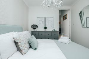 亨利昂泰晤士Central Hidden Gem的卧室配有带枕头和吊灯的白色床。