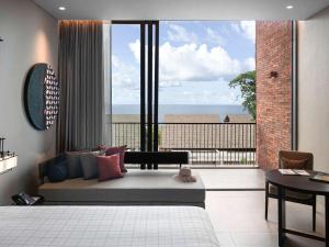 蔻立Pullman Khao Lak Resort的客厅在大窗户前配有沙发