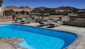 塞斯瑞姆Elegant Desert Lodge的一个带椅子的游泳池和一个背景为山脉的露台