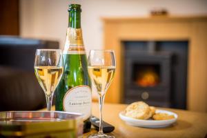 OtterhamSt Tinney Farm Cornish Cottages & Lodges, a tranquil base only 10 minutes from the beach的两杯白葡萄酒,旁边是一瓶香槟