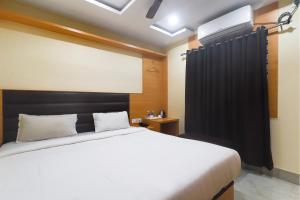 西里古里FabExpress Ganpati 2的卧室配有白色的床和黑色窗帘