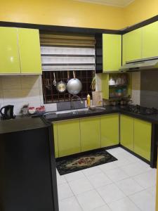 阿罗士打D'illahs Homestay的厨房配有石灰绿色橱柜和瓷砖地板。