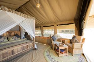 SinoniAfrica Safari South Serengeti Ndutu Ngorongoro的帐篷内一间卧室,配有一张床和椅子