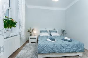 布拉格Alla Prague Apartment的白色卧室设有蓝色的床和窗户