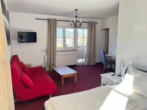 蒂罗尔-泽费尔德Waldhotel Seefeld的酒店客房配有红色的沙发和床。