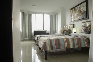 卡利Apartahotel Kelly的一间卧室设有两张床、一把椅子和一个窗户。