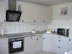GroßenwiehePetersen Uwe的厨房配有白色橱柜和微波炉