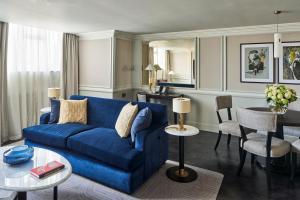 伦敦The Royal Horseguards Hotel, London的客厅配有蓝色的沙发和桌子