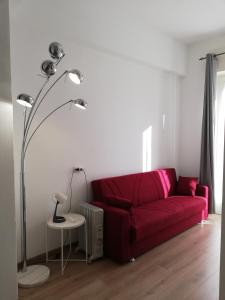 加拉瑞特Palazzo Pasta Malpensa的客厅里红色的沙发,配有灯