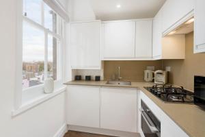 伦敦Luxury Chelsea Flat的白色的厨房配有白色橱柜和窗户