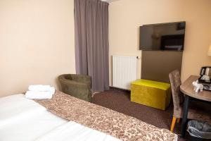 威斯巴登威斯巴登城市酒店的一间酒店客房,配有一张床铺、一张桌子和一台电视