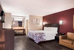 图珀洛图珀洛红屋顶酒店的配有一张床和一把椅子的酒店客房