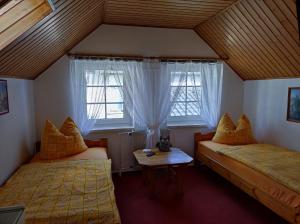 FlechtingenPension "Am Park" - Hofappartements的一间卧室设有两张床、一张桌子和两个窗户。