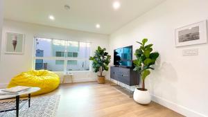 洛杉矶Kingsley Courtyard Apartment的一间带电视和黄色搁脚凳的客厅