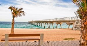 巴达洛纳Badalona playa Barcelona的坐在码头附近的海滩上的长凳