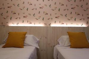 洛斯马蒂雷斯201 I Posada del Mar I Encantador hostel en la playa de Gandia的两张床,带黄色枕头,位于一间墙上的房间