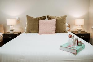 詹伯茹The Lodge Jamberoo的一间卧室配有一张带粉红色枕头和两盏灯的床。