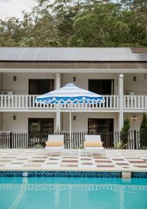 詹伯茹The Lodge Jamberoo的一座带游泳池、两把椅子和一把遮阳伞的房子