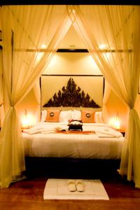 利巴诺伊Kanok Buri Resort的一间卧室配有床、窗帘和两双鞋