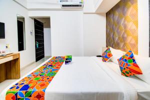 浦那FabExpress Marvel Bliss Viman Nagar的一间卧室配有一张大白色的床和色彩缤纷的毯子