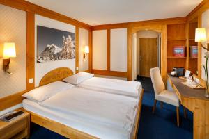 格林德尔瓦尔德德比瑞士品质酒店的酒店客房配有一张床、一张书桌和一张书桌。