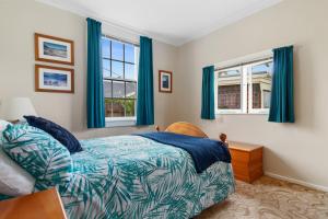 泰晤士Whare Nui on Rennie - Thames Holiday Home的一间卧室设有一张床和两个窗户。