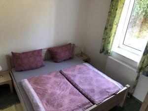 萨斯尼茨Villa Bella Vista - Meerblick 2的紫色枕头和窗户的客房内的一张床位