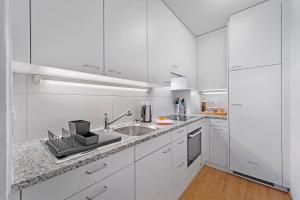 圣莫里茨Abitaziun Belmunt 103 - St Moritz "LOGA ELEGANCE APARTMENT"的白色的厨房配有白色橱柜和水槽