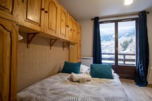 于埃Charming studio with beautiful view - Huez - Welkeys的一间卧室配有一张带蓝色枕头的床和一扇窗户。