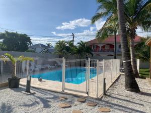 埃唐萨莱莱班海滩LE NID TROPICAL的棕榈树游泳池旁的围栏